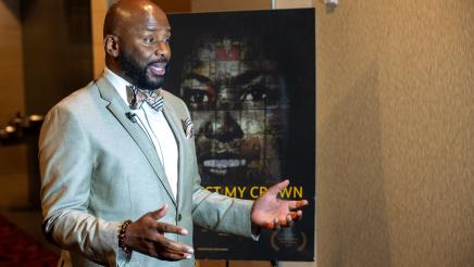 Asm. Gipson speaking in front of Respect My Crown poster