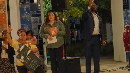 Asm. Gipson holding up candle, alongside other candle-holding participants