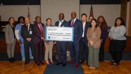 Group photo of Asm. Gipson and others holding up large ceremonial check