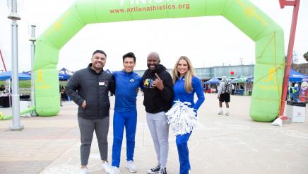 Asm. Gipson with LA Rams cheerleaders in front of inflatable arch